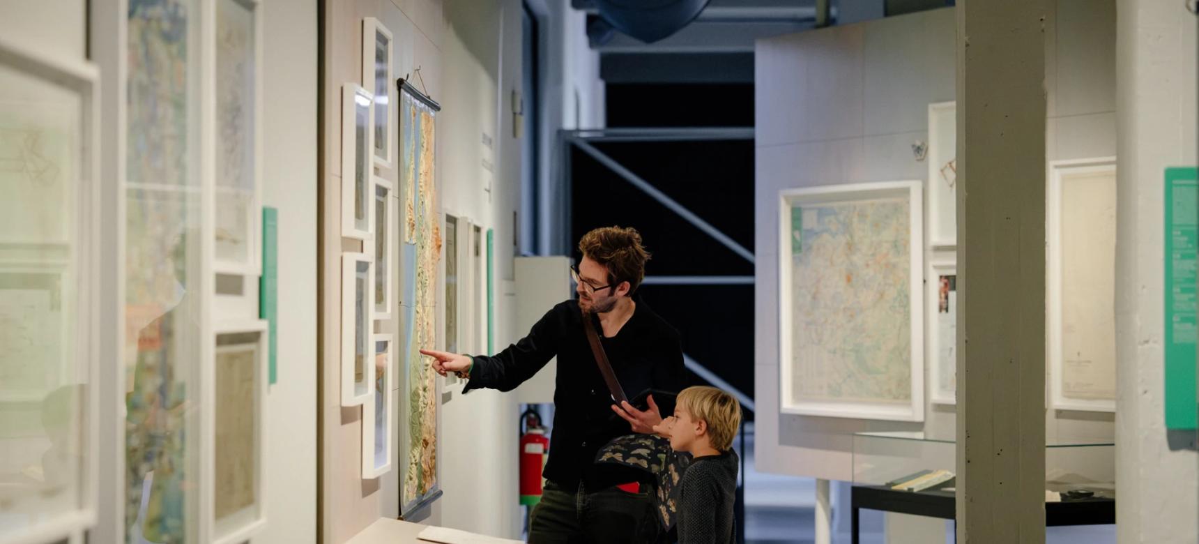 Gids vertelt kind meer informatie over de kaarten in MAP Mercator