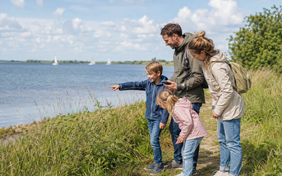 Een gezin zoekt een geocache langs het water