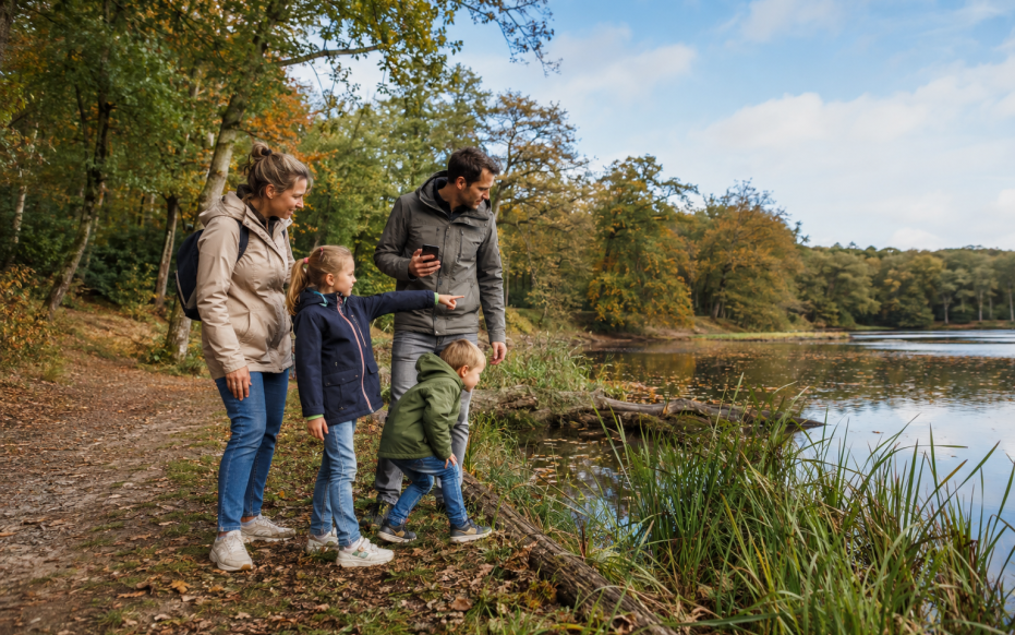 Een gezin zoekt een geocache langs het water